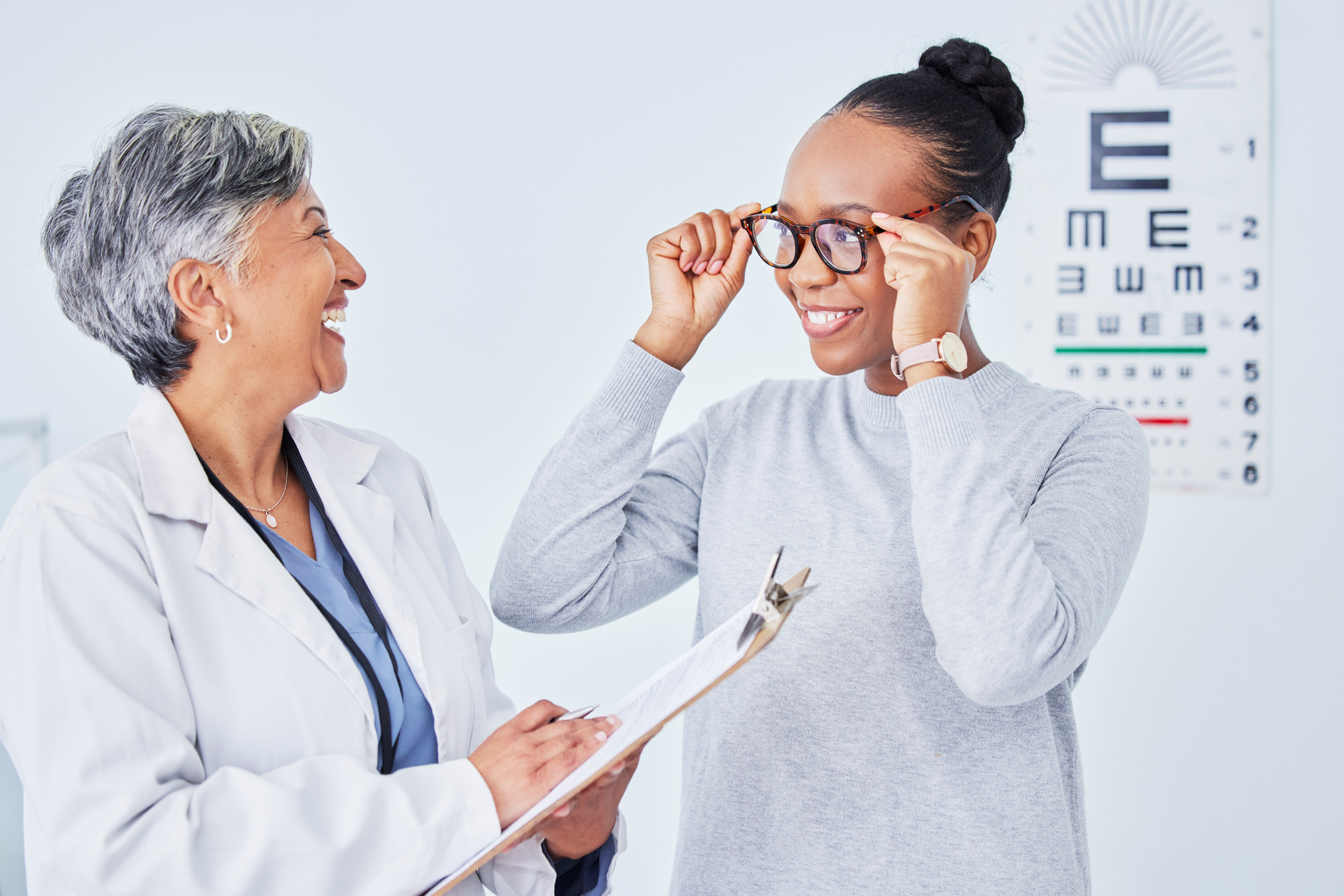 Optometrist smiling at patient trying on glasses 