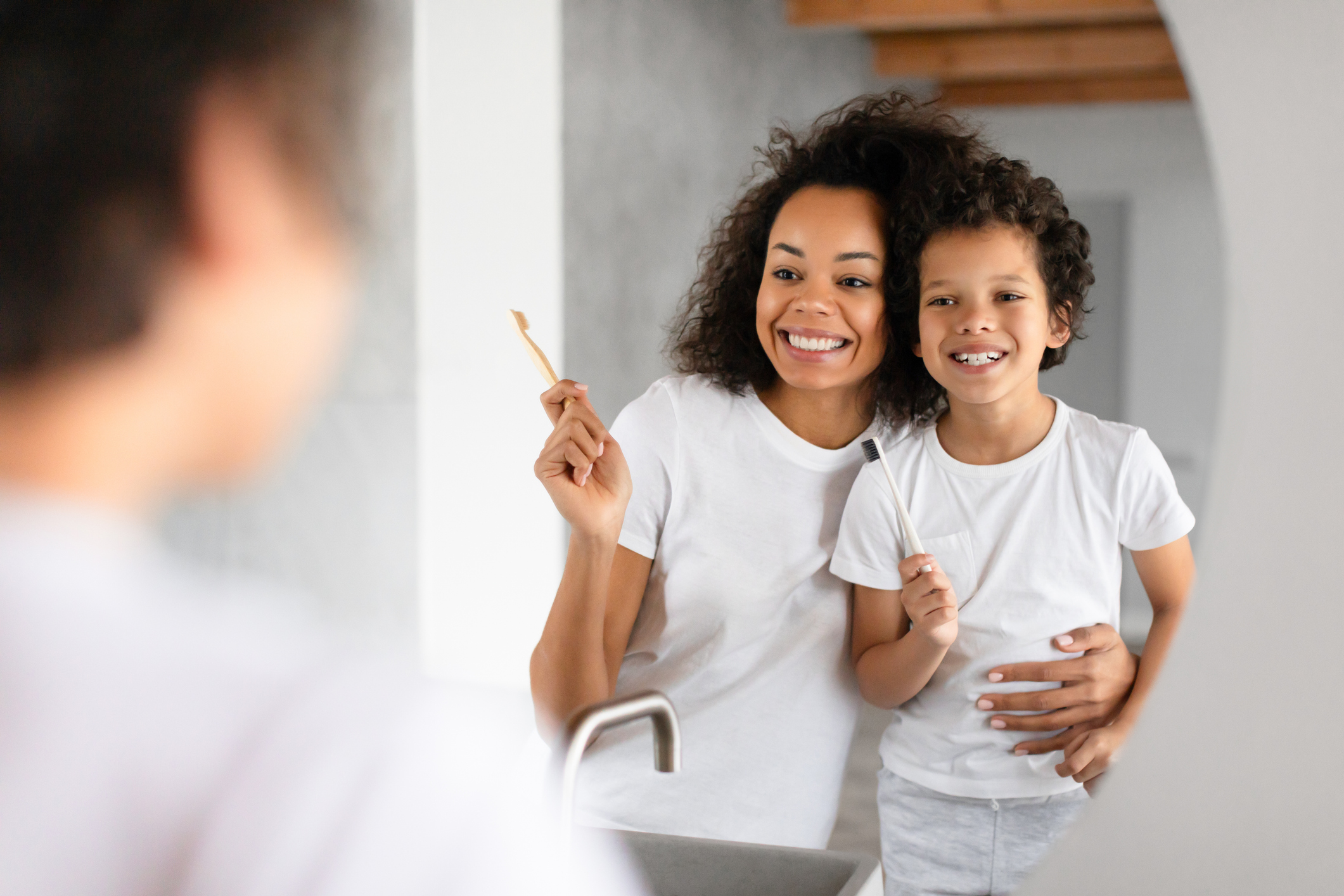 Mother and son brushing teeth together while looking in the mirror
