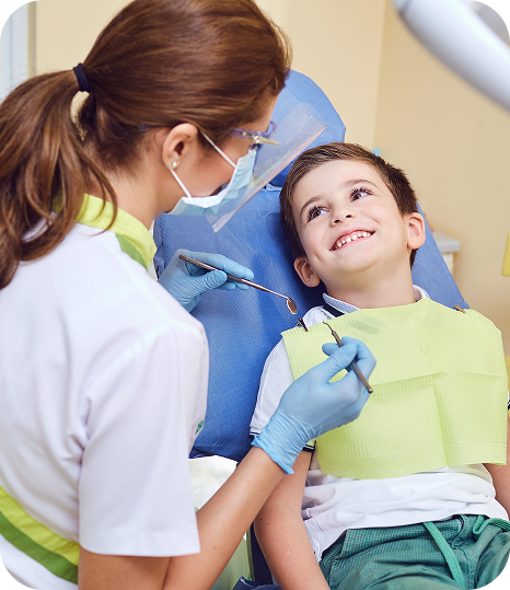 Young boy sitting in dentist's chair as the hygienist cleans his teeth.